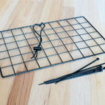 Black grid with cord, toggle, and zip ties to make DIY wedge feeder for chickens