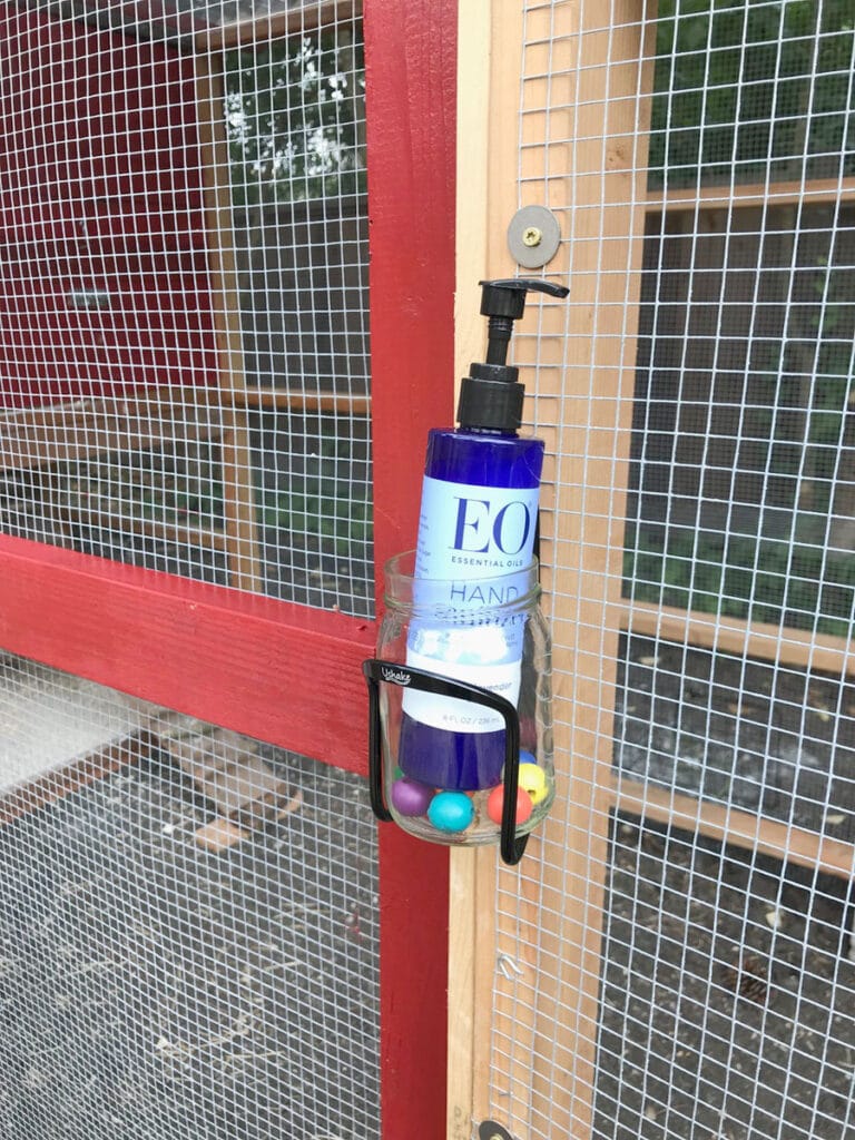 Squirt bottle of hand sanitizer mounted by the door of a chicken coop