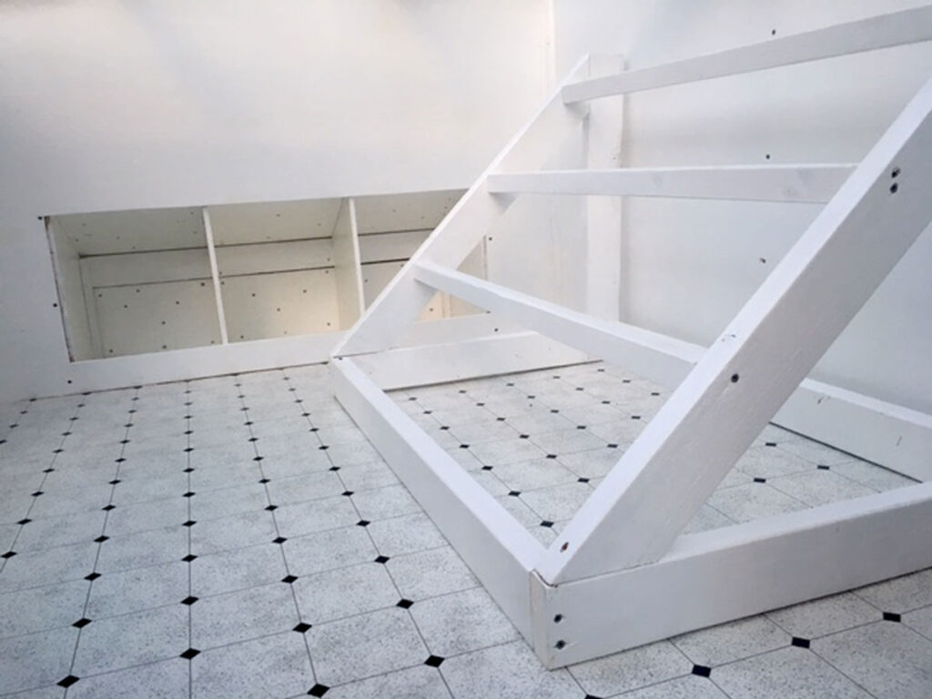 White three-perch ladder style roost inside the henhouse of a backyard chicken coop