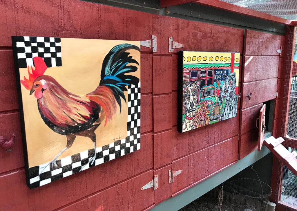 Pinturas con motivos de gallinas en la pared de un gallinero pintado de rojo en el patio trasero.