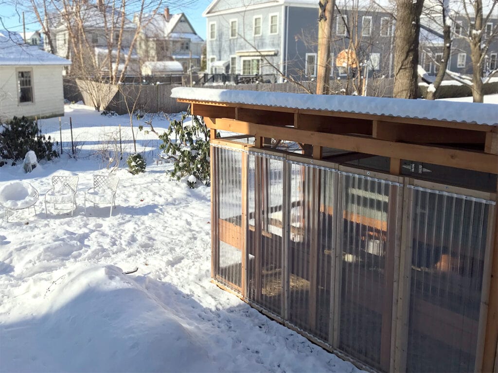 Gallinero Garden Loft en un patio trasero nevado con paneles de invierno